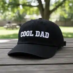 Black unstructured cotton dad hat with COOL DAD embroidery, curved brim and adjustable metal strap